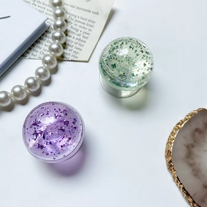 Close-up of glitter-filled crystal ball phone grips in light purple and green tones