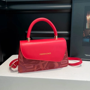 Elegant red leather crossbody bag with gold lettering and geometric prints on white steps