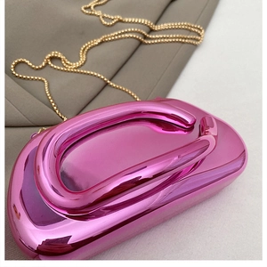 Gros plan d'une pochette en acrylique fuchsia avec finition métallisée et chaîne dorée