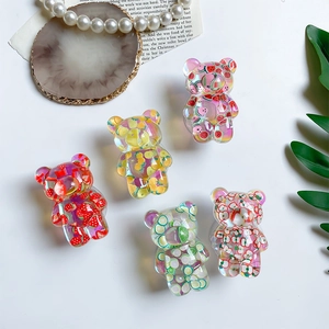 Flat lay of five transparent resin bear phone grips with colorful fruit slice inserts