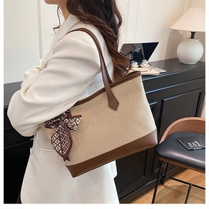 Detail of canvas tote bag with brown leather trim and decorative silk scarf on handle