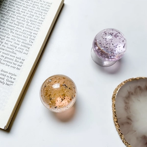 Close-up of translucent crystal ball phone grips with purple and amber gold foil accents
