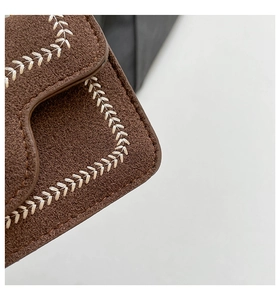 Detail of dark brown suede bag featuring exquisite cream embroidery stitching on edges