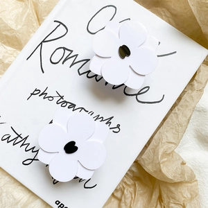 Close-up of two black and white camellia flower phone grips on an artistic book background
