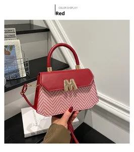 Close-up of red leather and white herringbone weave crossbody bag with golden M metal hardware