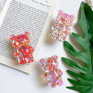 Detail of transparent bear phone grips with embedded fruit patterns on book page
