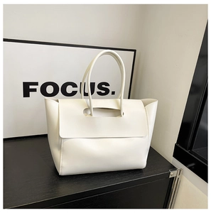 Vista macro della borsa tote minimalista bianca con chiusura a patta e spalline sottili