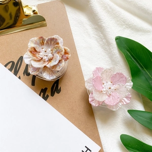 Detailed macro view of 3D resin flower phone grip with pearl center and marble texture