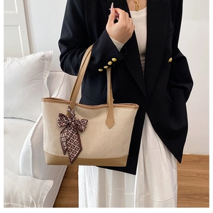 Detail der beigen Canvas-Tasche mit Lederbesatz und dekorativem Seidentuch am Griff
