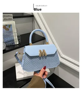 Detail of blue leather and woven fabric small handbag with gold M logo buckle