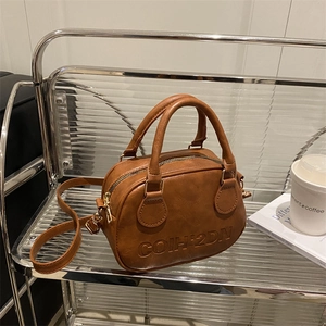 Caramel brown leather mini Boston bag with embossed lettering and golden zipper detail