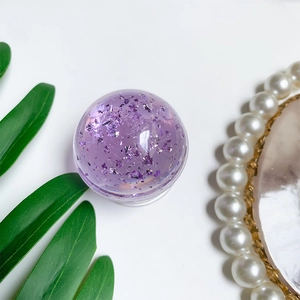 Detail of purple crystal ball phone grip with metallic flakes on a white aesthetic desk