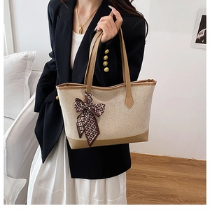 Detail of canvas tote bag with brown leather trim and decorative patterned silk scarf