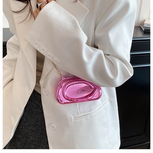 Gros plan d'une pochette rose géométrique avec chaîne dorée sur un blazer blanc