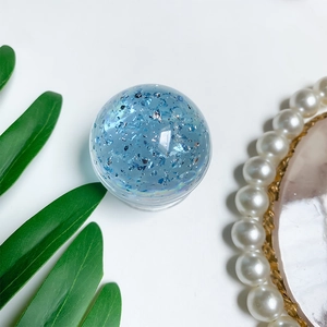 Detailed view of a light blue transparent crystal ball phone grip with silver glitters