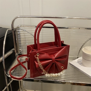 Sac à main rouge avec nœud et chaîne perlée exposé pour un style élégant féminin