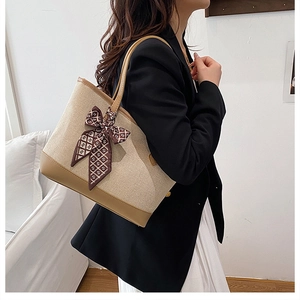Detail of canvas tote bag with silk scarf ribbon and leather trim on a model