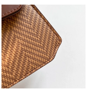 Détail de la paille tressée texturée et des coutures en cuir marron sur le sac à main
