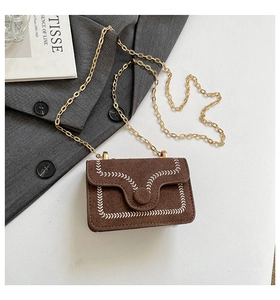 Detail of brown faux suede chain bag featuring white wheat embroidery and golden strap
