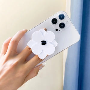 Detailed view of a white camellia flower phone socket grip being held by hand