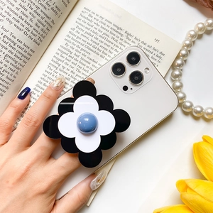 Détail d'un support de téléphone en forme de fleur posé sur un smartphone moderne