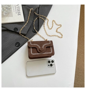 Mini brown suede crossbody bag with gold chain shown next to smartphone for scale