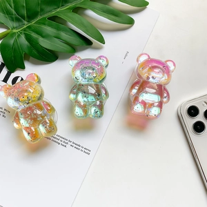Close-up of glittery resin bear phone grips in gradient colors on aesthetic background
