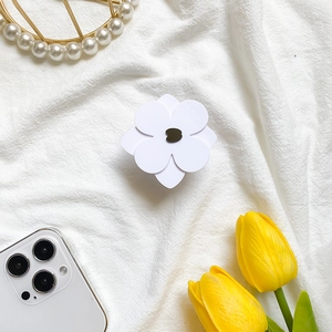 Close-up of minimalist white flower phone grip holder on textured white fabric