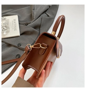 Détail du cuir tressé marron et des boucles dorées sur le sac à bandoulière