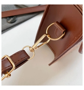 Détail de la ferrure dorée et de la boucle sur un sac bandoulière en cuir marron foncé