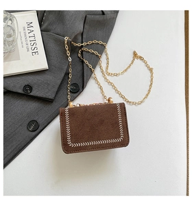 Detailed close-up of brown suede crossbody bag with elegant white stitch accents and gold chain