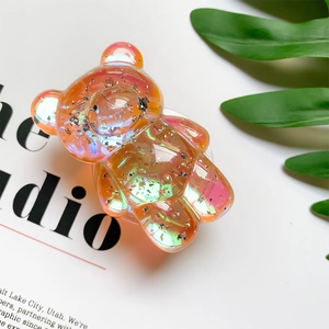 Close-up of a 3D translucent orange bear phone grip with glitter and iridescent finish