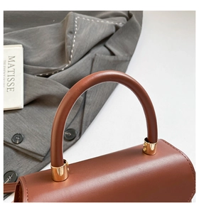 Gros plan détaillé d'un sac à main en cuir marron avec boucle dorée et poignée ronde