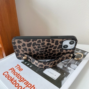 Detail of leopard print phone case featuring a gold studded hand strap and metal ring