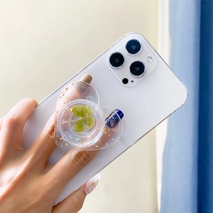 Detail of heart-shaped phone grip with real green clover and gold foil in resin