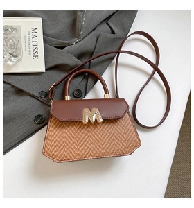Détail d'un sac bandoulière vintage en cuir marron, texture tissée et boucle dorée en M