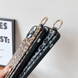 Close-up of leopard print phone case with leather texture, gold rivets and metal ring strap