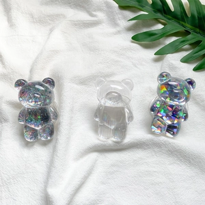 Detailed close-up of three bear phone holders in glittery, clear, and laser finishes