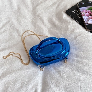 Pochette en acrylique bleu brillant avec chaîne dorée sur un tissu blanc doux