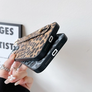 Detailed view of leopard print phone case featuring a gold buckle wrist strap and stand