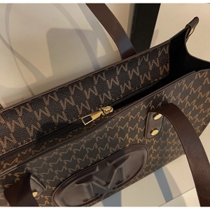 Detailed shot of monogram print tote with gold hardware and secure zipper closure
