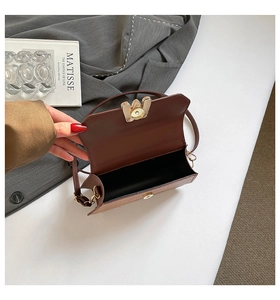 Détail d'un sac bandoulière marron foncé texturé avec fermoir métallique doré et doublure