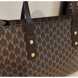 Detail of the brown tote bag featuring M-letter monogram print and golden metal rivets