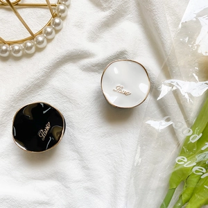 Detail of round black and white phone grips with golden Love script on pleated fabric