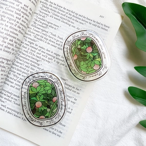 Close-up of clear acrylic phone grips featuring green leaf floral patterns on a book