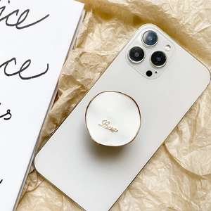 Macro detail of white collapsible phone grip with gold Love script on minimalist phone