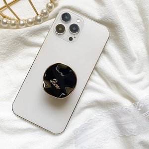 Minimalist black and gold LOVE collapsible phone socket grip on white smartphone
