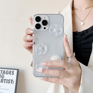 Détail de la coque iPhone avec fleurs 3D mates et perles blanches tenue par un modèle