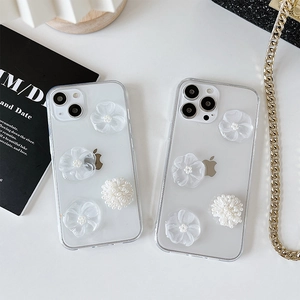Détail de coque iPhone avec fleurs 3D blanches et perles sur coque souple transparente