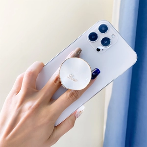Detail of elegant white and gold Love phone grip held by hand on a smartphone